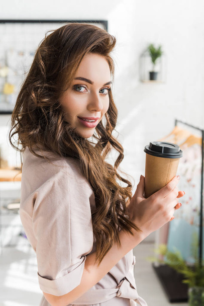 beautiful young woman looking at camera while holding disposable cup  - Photo, Image