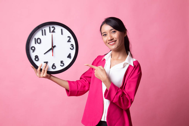 Young Asian woman point to a clock. - Zdjęcie, obraz