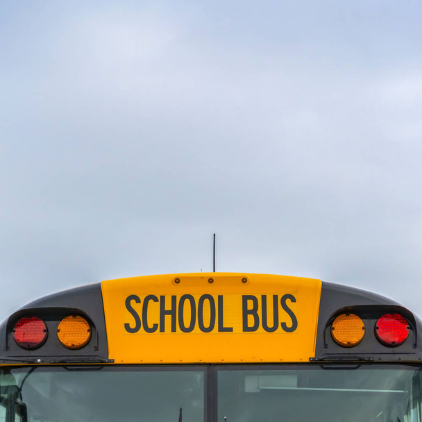 Place Vue de face d'un autobus scolaire jaune avec des maisons et ciel nuageux en arrière-plan
 - Photo, image