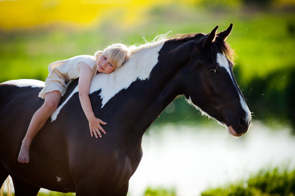 Criança senta-se em um cavalo
 - Foto, Imagem