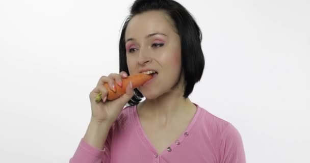 Mujer joven comiendo zanahoria y dice ñam. Chica toma primer mordisco y decir quiero morder
 - Metraje, vídeo