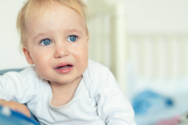 Cute caucasian blond toddler boy portrait crying at home during hysterics. Little child feeling sad. Small pensive baby after quarell - Photo, Image