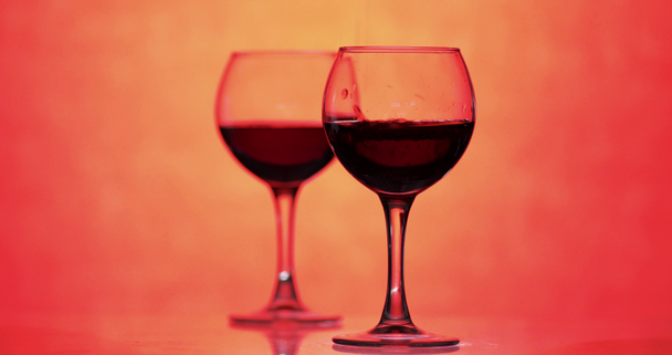 Růžové víno. Červené víno nalijte do skleněného vína přes oranžové pozadí - Záběry, video