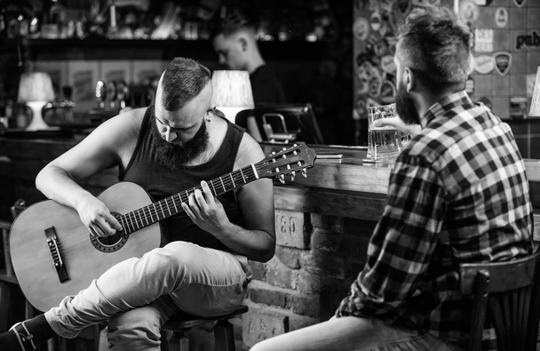 Friday relaxation in bar. Friends relaxing in bar or pub. Hipster brutal bearded spend leisure with friend in bar. Real men leisure. Cheerful friends relax with guitar music. Man play guitar in bar - Fotografie, Obrázek