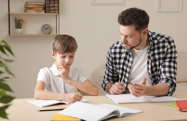 Dad struggling to help his son with school assignment at home - Foto, afbeelding