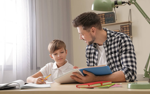 Dad helping his son with school assignment at home - Foto, afbeelding