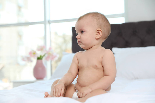 Cute baby in diaper on bed at home - Photo, image