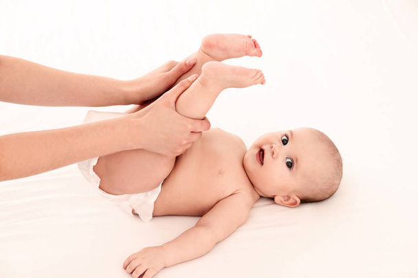 Mother and her cute child on white bed. Baby massage and exercises - Photo, image