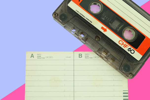 Стара касетна стрічка аудіо з папером для написання назви пісні та тексту на рожевому фоні. Гаджети аксесуари для 70-80-90-х років
 - Фото, зображення