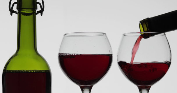 Rose wijn. Rode wijn pour in twee wijn glazen over witte achtergrond - Video