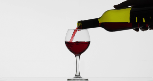 Růžové víno. Červené víno nalít do skleněného vína přes bílé pozadí - Záběry, video