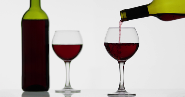 Rose wijn. Rode wijn pour in wijn glas over witte achtergrond - Video