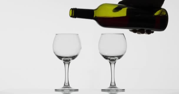 Rosenwein. Rotwein in zwei Weingläser auf weißem Hintergrund gießen - Filmmaterial, Video