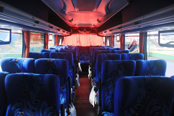 Blue seats with plastic trash bags at the side in a bus with red curtains from south america - Foto, Imagen