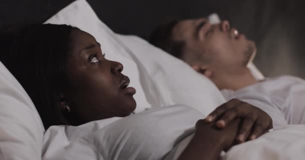 Multi-ethnic couple lying in bed together. Woman suffers from her partner snoring in bed. Couple lifestyle and people health care concept. - Felvétel, videó