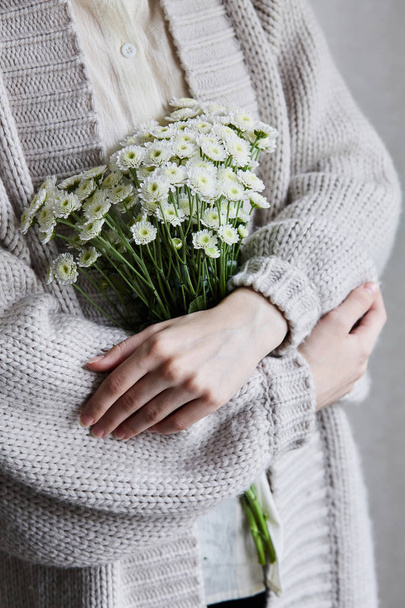 photo of young woman holding white flowers with green stem in her hands - Fotó, kép