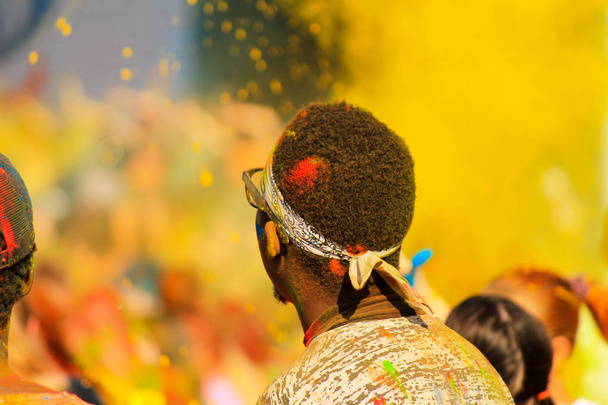 Afrikaanse jongen student met kleur bedekt haar plezier op de achtergrond van gele verf op de Holi Festival in de lente, de zomer, Dnipro stad, Oekraïne - Foto, afbeelding