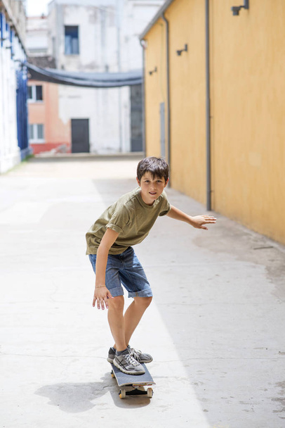 Вид спереди веселый мальчик катается на коньках по улице в солнечный день
 - Фото, изображение