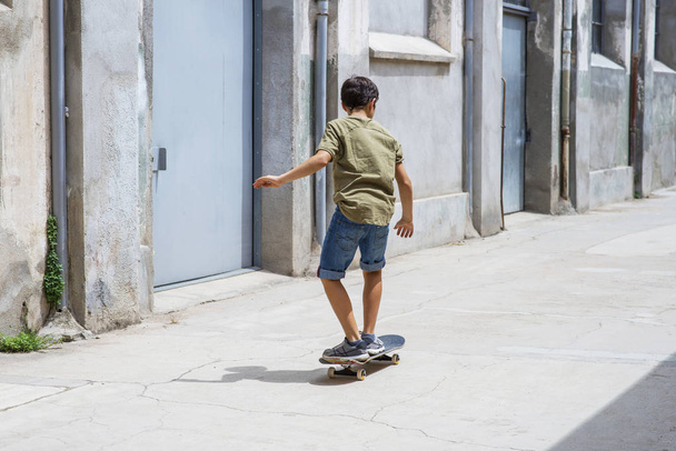 Vooraanzicht van een vrolijke Skater jongen rijden op de straat in een zonnige dag - Foto, afbeelding