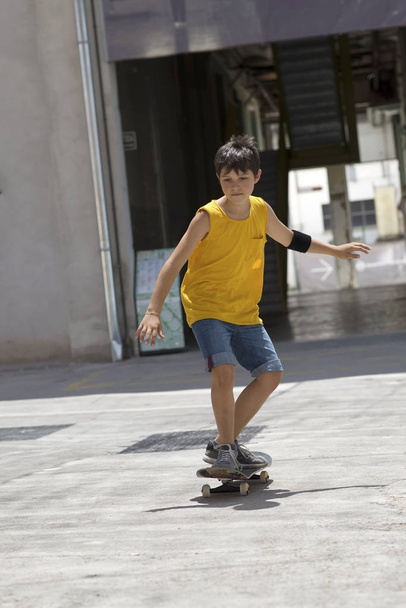 Frontansicht eines fröhlichen Skater-Jungen, der an einem sonnigen Tag auf der Stadt reitet - Foto, Bild