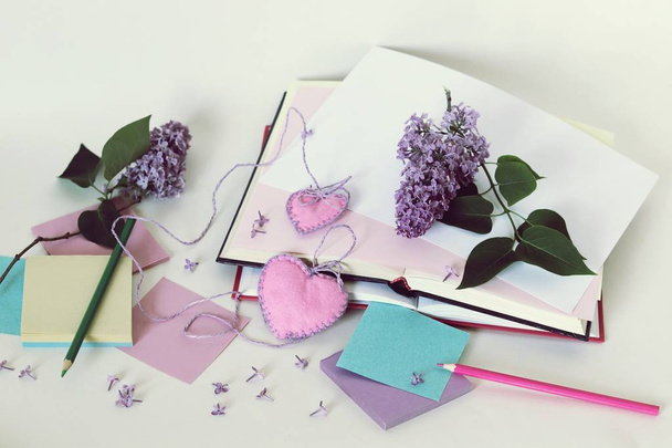 オープンブック、ブックマークの心、紙、鉛筆、テーブルの上にライラックの花の枝、ロマンチックな本を読んで、あなたの考えを書き留めます - 写真・画像