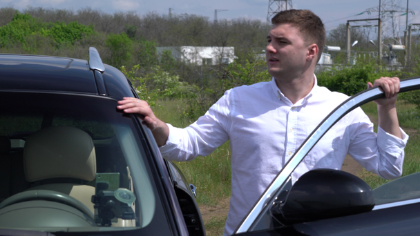 Jongeman verlaat een geparkeerde auto op het platteland - Video