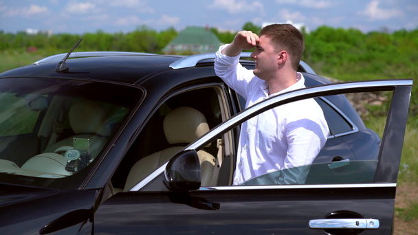 Junger Mann steigt aus einem geparkten Auto - Filmmaterial, Video
