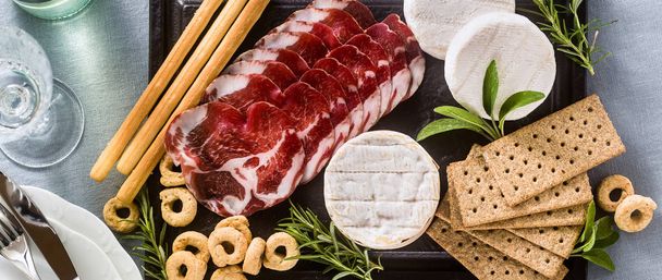 banner of cold cuts and cheese are served on a tray on a table w - Foto, afbeelding