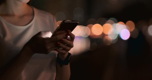 Nahaufnahme eines Mobiltelefons in den Händen eines Mädchens in der Stadt in der Nacht - Filmmaterial, Video