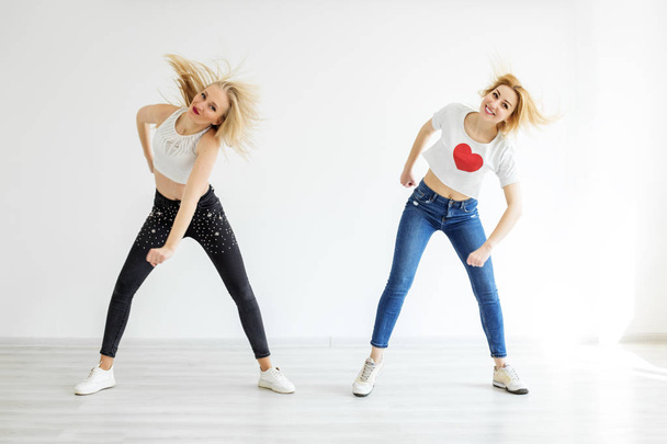 Deux jeunes filles dansant en jeans et baskets. Le concept de sport, de danse et de style de vie
 - Photo, image