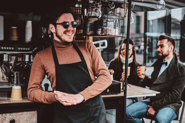 Привлекательный веселый бариста в солнцезащитных очках взял перерыв на кофе в своем собственном кафе
 - Фото, изображение