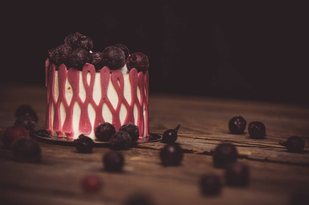 festive cake with the fruits of cherry on a rustic wooden table on a dark background. close up copy space. vintage pattern on dessert tartlet. birthday holiday - 写真・画像