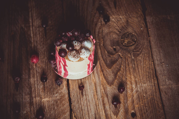 festive cake with the fruits of cherry on a rustic wooden table on a dark background. close up copy space. vintage pattern on dessert tartlet. birthday holiday - Photo, image