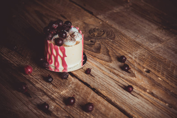 festive cake with the fruits of cherry on a rustic wooden table on a dark background. close up copy space. vintage pattern on dessert tartlet. birthday holiday - Foto, afbeelding