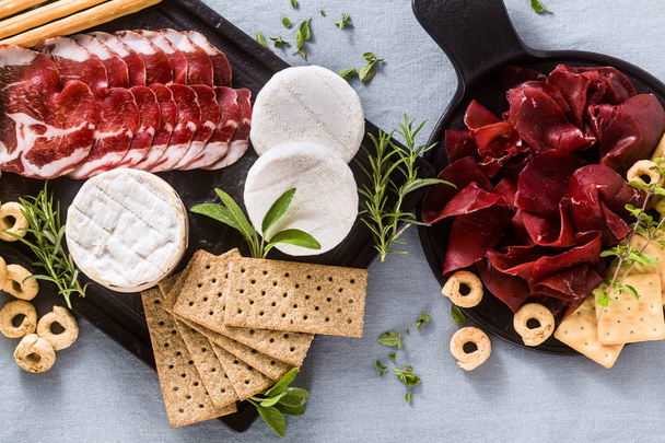cold cuts and cheese are served on a tray on a table with white  - Foto, imagen