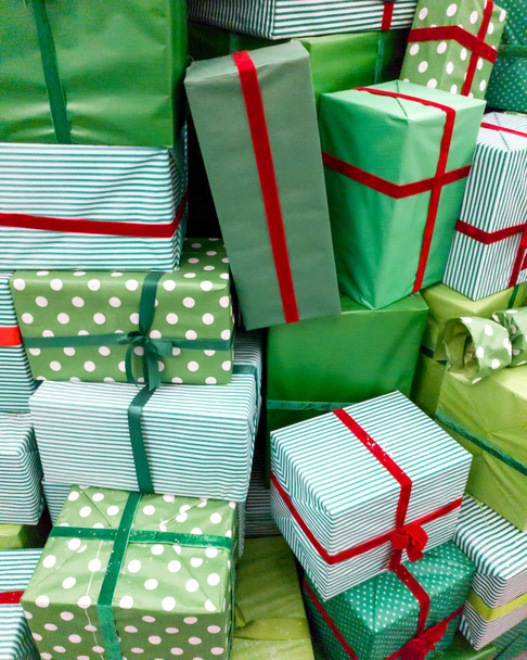 クリスマスプレゼントの山のクローズアップ画像。新年のプレゼントと赤いリボンと緑のボックスのスタック - 写真・画像