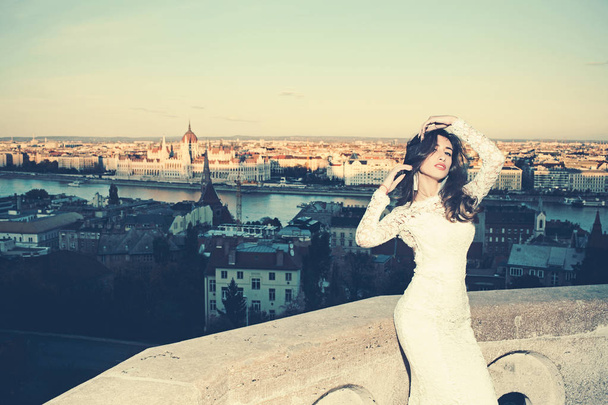 Bride woman in white wedding dress on city view. Bride with long hair on balcony. - Photo, Image