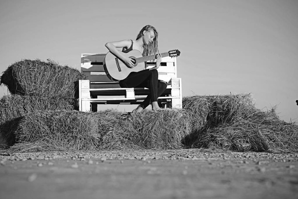 Girl play guitar on wooden bench. Girl guitarist perform music concert - Фото, зображення