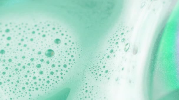Close-up van zeep schuim in licht groen pastel water. 4k-macro beelden. - Video