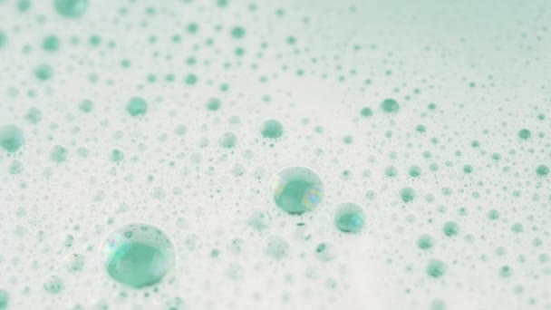 Gros plan de mousse de savon dans de l'eau pastel vert clair. Images macro 4K
. - Séquence, vidéo