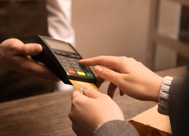 Женщина с кредитной картой с помощью платежного терминала в магазине, крупным планом
 - Фото, изображение