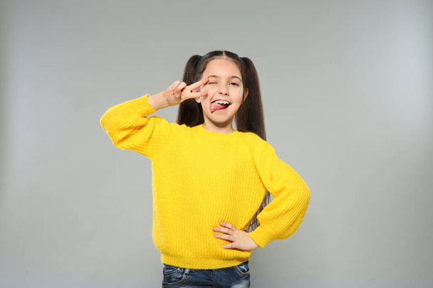 Portrait of little girl posing on grey background - Фото, изображение