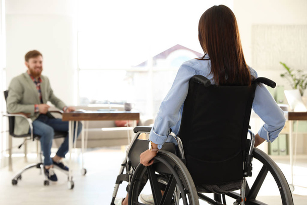 Young woman in wheelchair with colleague at office - Φωτογραφία, εικόνα