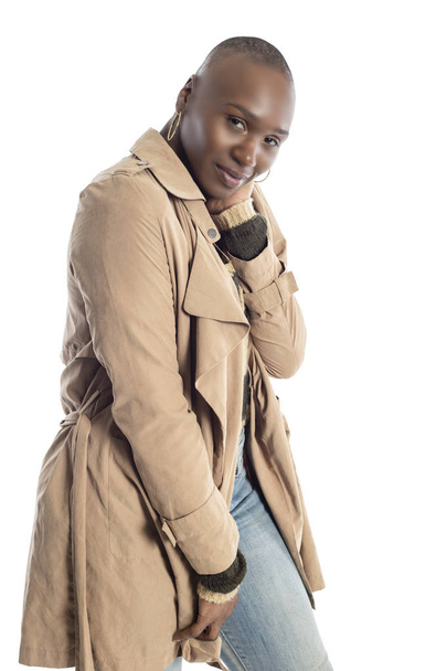 Confident black African American female model wearing Fall or Spring style fashion with a jacket or coat and jeans.  She has a bald hairstyle and isolated on a white background.   - Фото, зображення