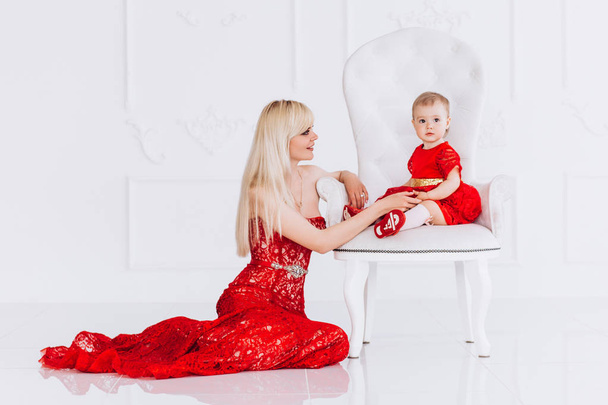 Nice, family, good photo of mother and daughter in red dresses in the studio. Mothers Day and daughters. Advertising family values and traditions. - Foto, Imagem