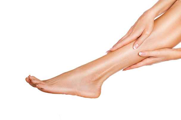 Femme massant ses jambes isolées sur fond blanc. Vue rapprochée d'une jambe féminine avec une peau et des mains parfaites
 - Photo, image
