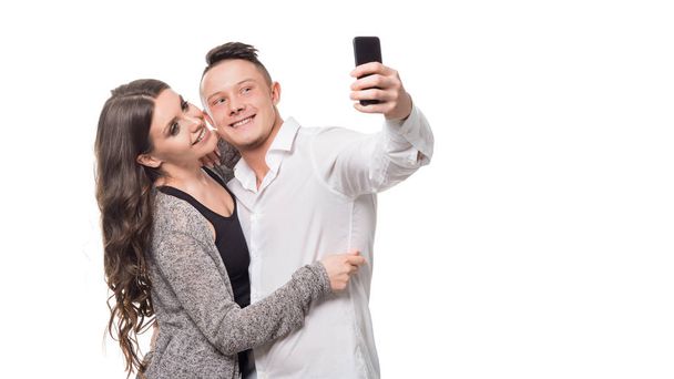 Čas selfie. Krásný mladý pár, který se usmívá a směje se, když stojí na bílém izolovaném pozadí. - Fotografie, Obrázek