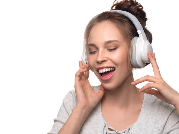 Menina atraente com fones de ouvido no fundo branco
 - Foto, Imagem