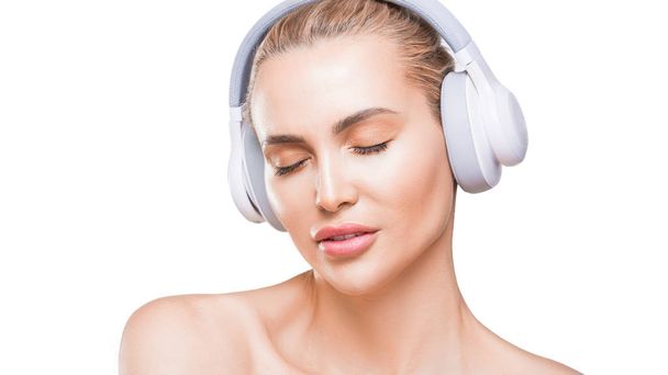 bela mulher em fones de ouvido brancos escuta música com olhos fechados no fundo branco
 - Foto, Imagem