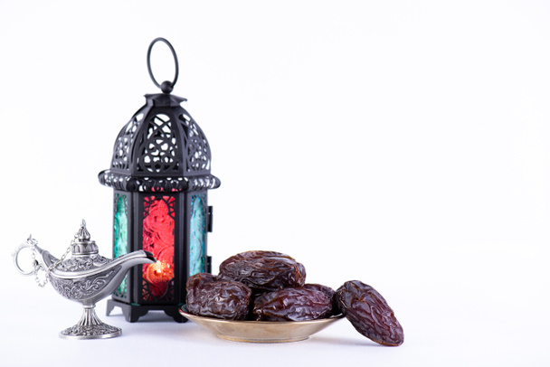 Concepto de comida y bebida del Ramadán. Linterna Ramadán con lámpara árabe, rosario de madera, dátiles de fruta e iluminación sobre fondo blanco
. - Foto, imagen